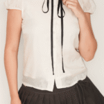 Blusa branca com mangas bufantes e saia plissada escura Soiko